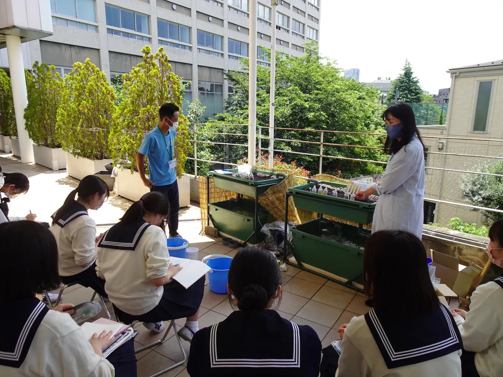 Students on the school terrace taking notes beside the media beds during a lesson